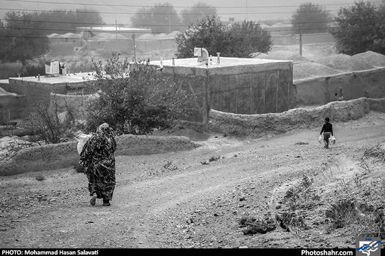  یکی از زنان روستای کلاته باغی در حال جا به جایی دبه آب از قنات به خانه؛ آب آشامیدنی بخش صالح آباد از طریق لوله کشی تامین می شود، اما فقط حدود ش