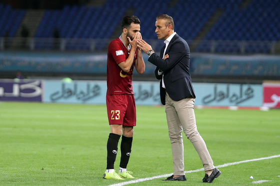 یحی گل محمدی سرمربی تیم شهر خودرو در کنار زمین در حال صحبت با یک یاز بازیکنان این تیم 