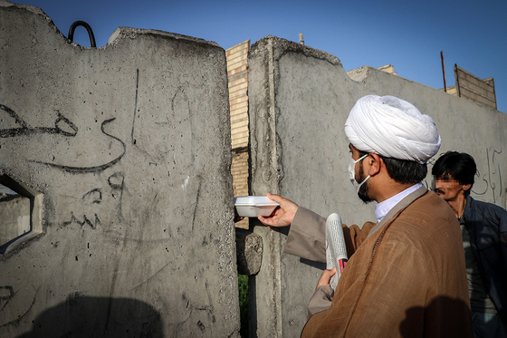 حجت الاسلام مظلوم از لابلای بلوکه های سیمانی بین کارتن خواب ها غذا توزیع میکند.